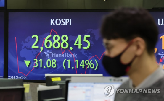 2月24日上午,在首尔市中区韩亚银行,交易员走过实时股价显示屏。(图源:韩媒)