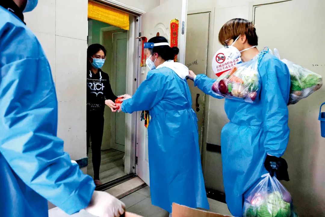 4月11日，上海普陀区锦绿新城居民区，社区志愿者为居民挨家挨户运送生活物资。 图/新华