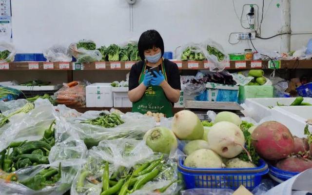 2022年4月26日下午,农光里市场,李秀兰在她开的蔬菜店里等待客人。新京报记者 汪畅 摄