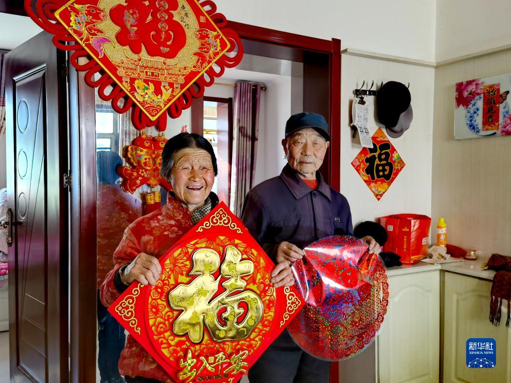 刘福有(右)和老伴在山西省忻州市岢岚县城移民搬迁小区的家中(2021年12月22日摄,手机照片)。新华社发