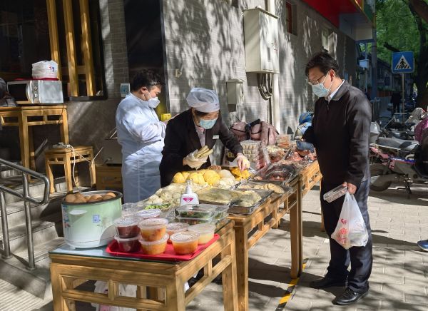 5月1日清晨，市民在北京佟麟阁路的庆丰包子铺和华天二友居肉饼店铺门前购买早餐（新华社发）