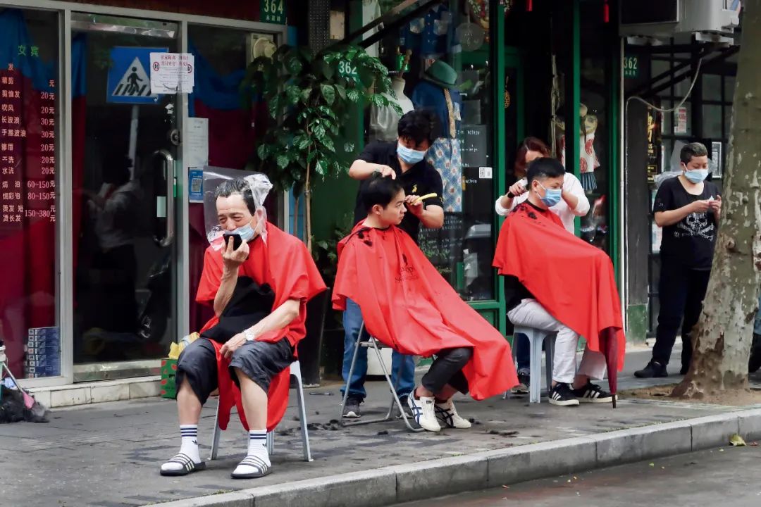 5月29日,理发师在上海街头为人们理发。图/人民视觉