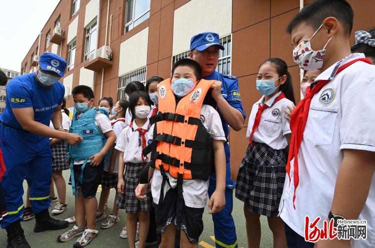 2022年6月28日,在河北省邯郸市邯山区滏河学校,邯郸蓝天救援队的队员为学生们讲解救生衣的使用方法。通讯员郝群英摄