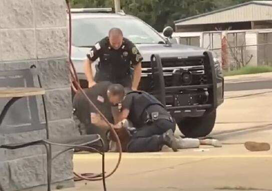 有一名警察将男子的头部从地上抓起,随后将后者的头砸向地面
