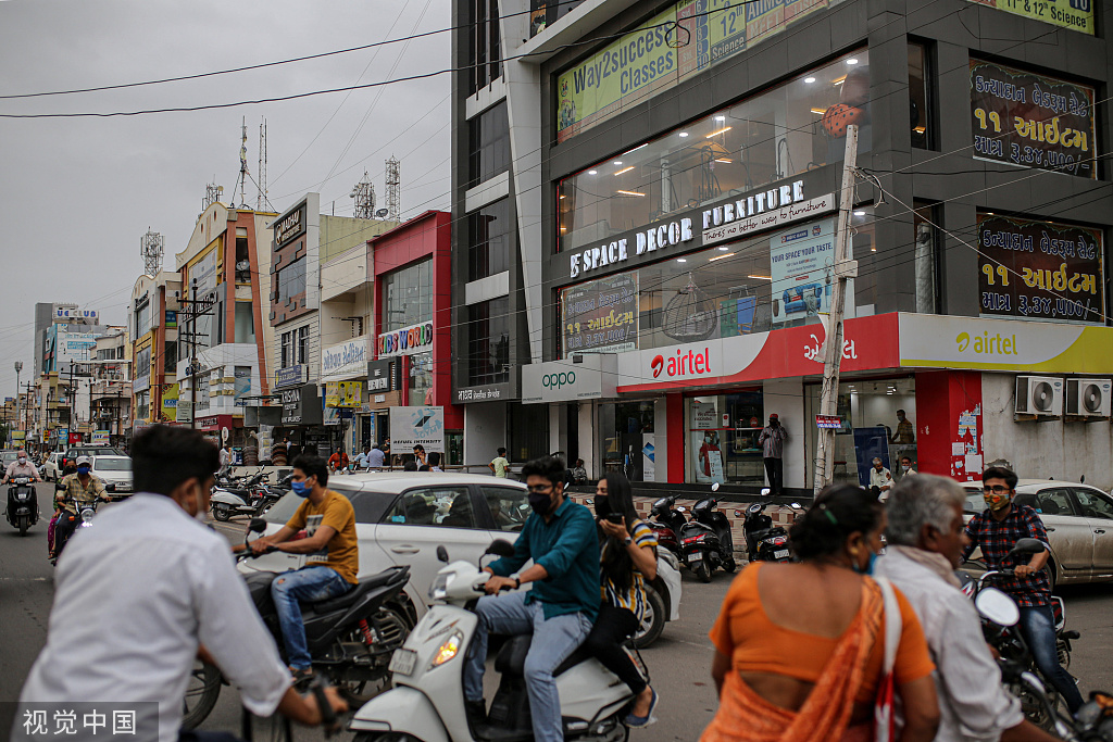 7月31日，印度古吉拉特邦，民众骑摩托在路过贾姆纳加尔的一个商店。（视觉中国）