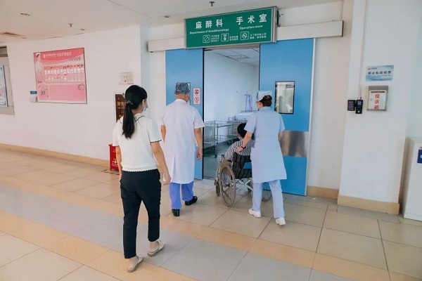 (在医护战友和妻子的陪同下,邓文军被推进手术室)
