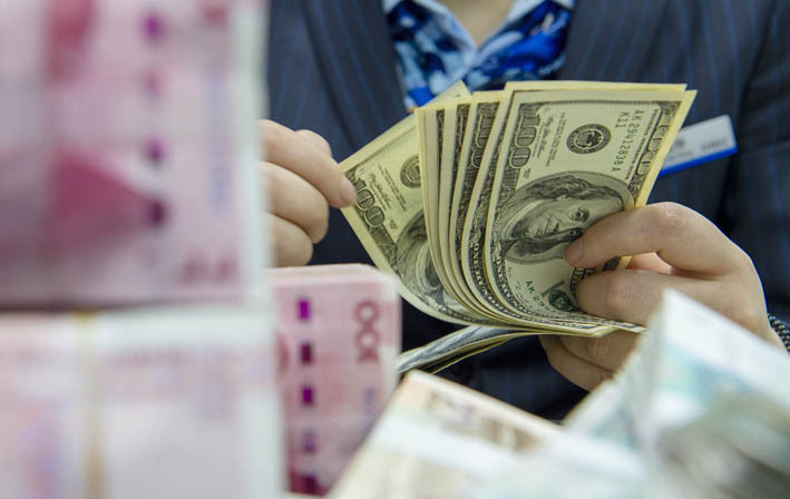 11月末外储规模环比上升2.13%。图为江苏省海安市一家银行的工作人员清点美元现钞 新华社图