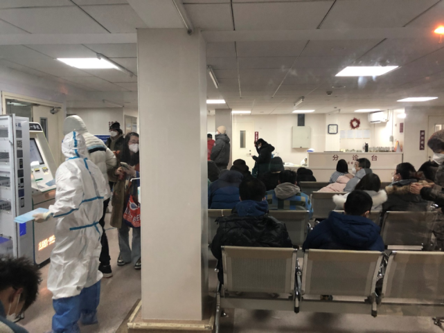 2022年12月12日晚,北京朝阳医院发热门诊分诊区坐满了患者,工作人员在一旁维持秩序。《财经》记者 金贻龙/摄