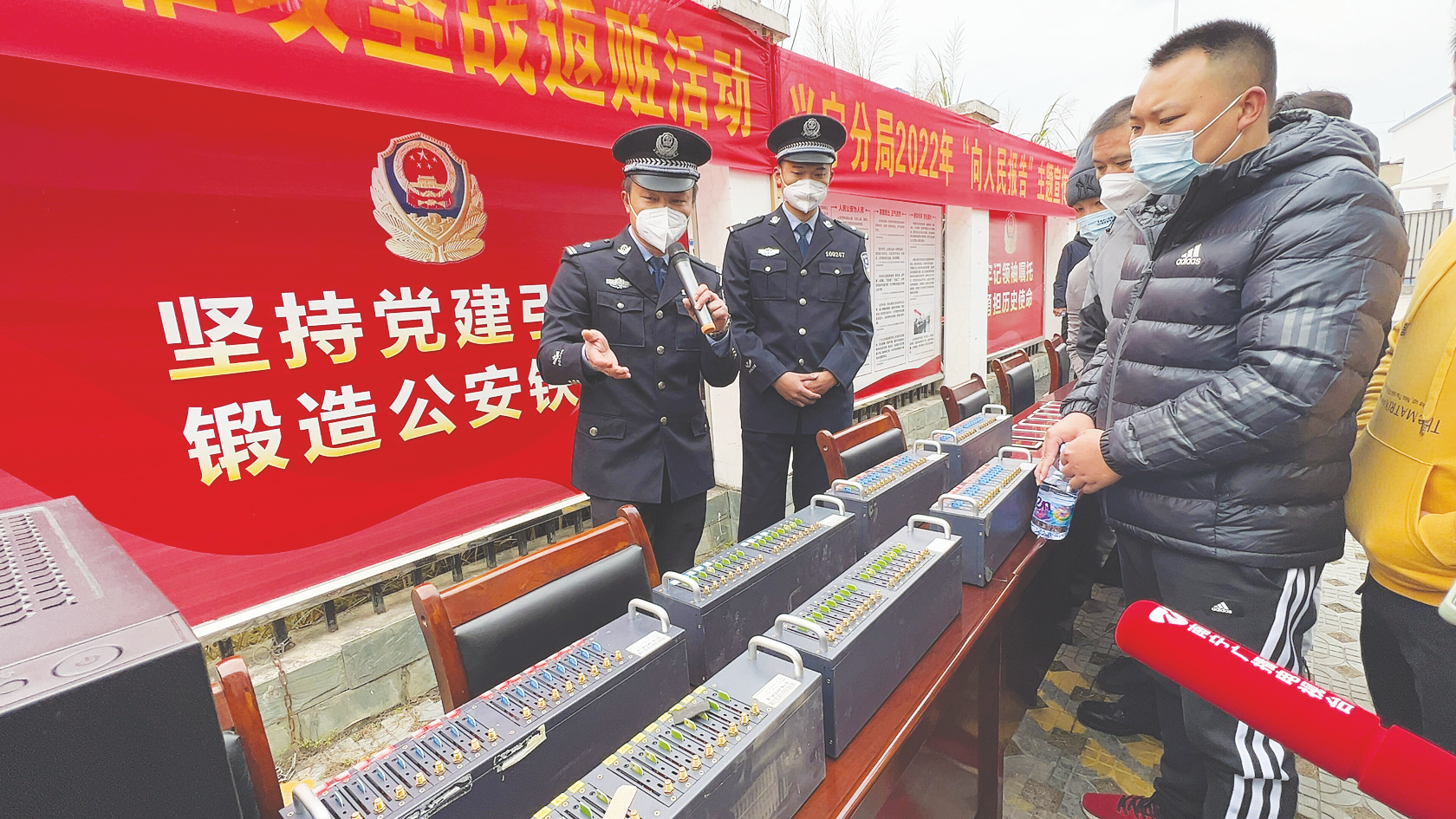 ▲民警向市民介绍电信网络诈骗分子如何使用工具骗人