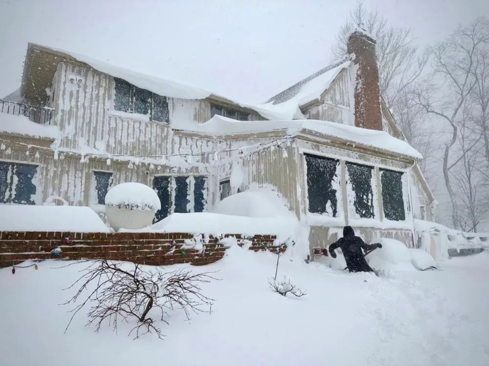 2022年12月24日，美国纽约州伊利县阿默斯特地区的居民在清理积雪。图片来源：新华社