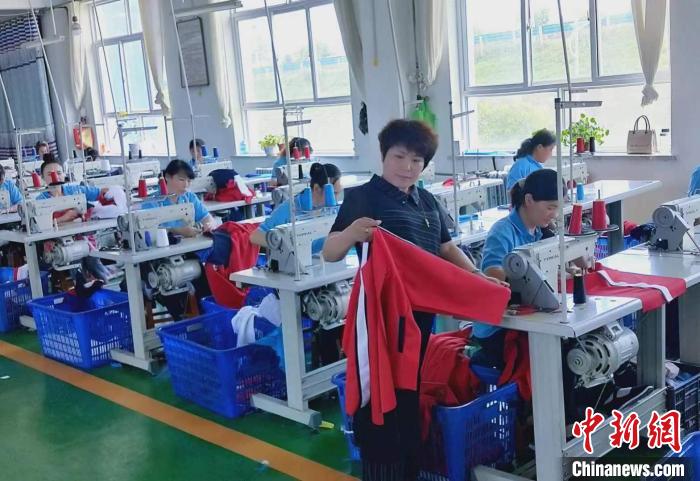 临夏县翠梦飞服装加工有限责任公司总经理唐小翠(中)在制衣工厂内检查衣服质量。(资料图) 受访人供图