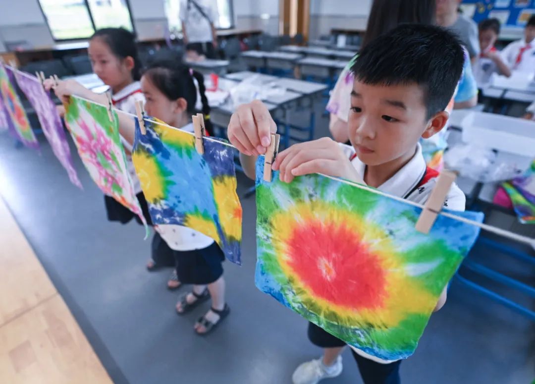 2022年8月10日，湖州市吴兴实验小学的学生把做好的扎染作品挂在教室里。新华社记者 徐昱 摄