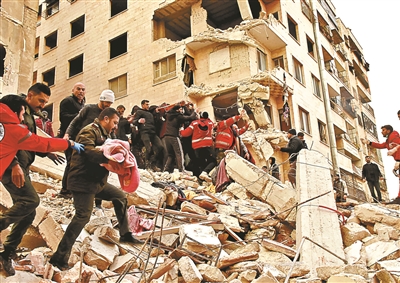 2月6日，人們在敘利亞哈馬省一處倒塌的建築上進行救援 供圖/新華社