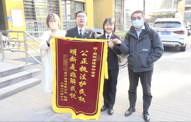 申请执行的公司代表(左一)向北京市朝阳区人民法院法官赠送锦旗。图源:北京市朝阳区人民法院