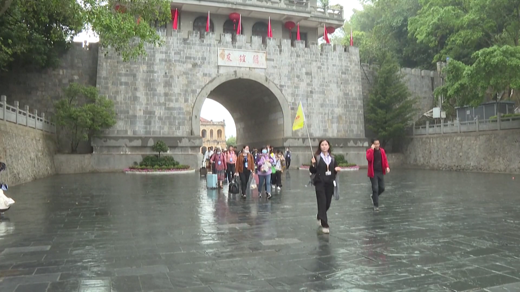3月15日,国内首批赴越旅游团游客在友谊关关楼前拍照留念。(图源:CCTV+)