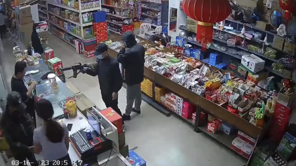 3月16日晚，女店员（左下穿淡紫色上衣长发女子）被绑匪持枪带走。视频截图