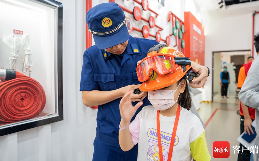 3月26日,南国小记者们走进海口市美兰区图书馆消防体验馆。图为消防员为小记者穿戴消防头盔。记者 李昊 摄
