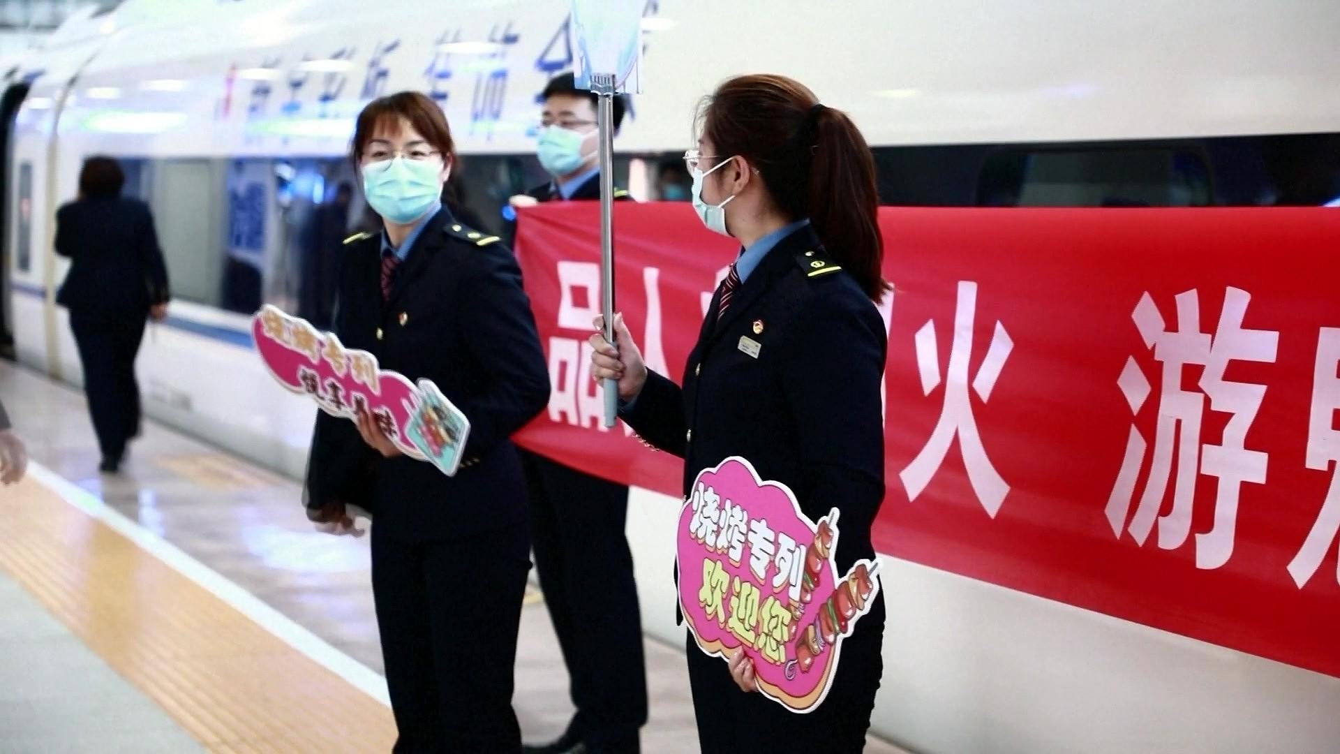4月23日,淄博烧烤专列人员手持纸板欢迎标语吸引游客 据视觉中国