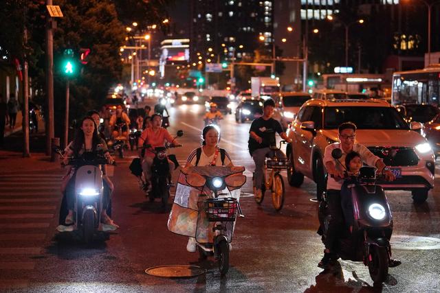 6月30日晚上8点，西大望路与南磨房路交叉路口，几名未佩戴安全头盔的骑行者通过路口。新京报记者 王贵彬 摄