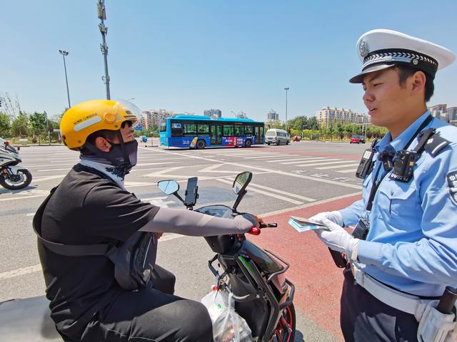 6月30日中午，交警向外卖骑手进行交通安全宣传。新京报记者 王贵彬 摄
