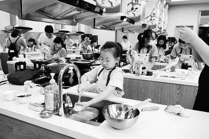 图:小朋友们在烹饪中心认真学习制作蛋糕。资料图片
