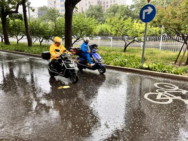 7月30日12时,北京海淀区车公庄西路,外卖骑手冒雨送餐。新京报记者 秦胜南摄
