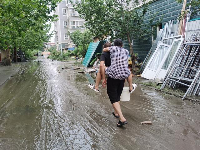 8月2日,小区地面上还是一片泥泞。一对老年夫妻打水归来。雷册渊 摄