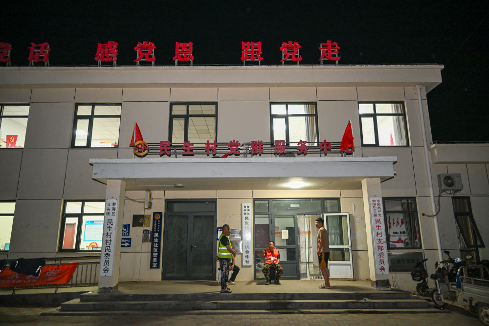 8月7日晚,村干部及留守人员在天津市静海区台头镇民生村村委会门外交谈。新华社记者 孙凡越 摄