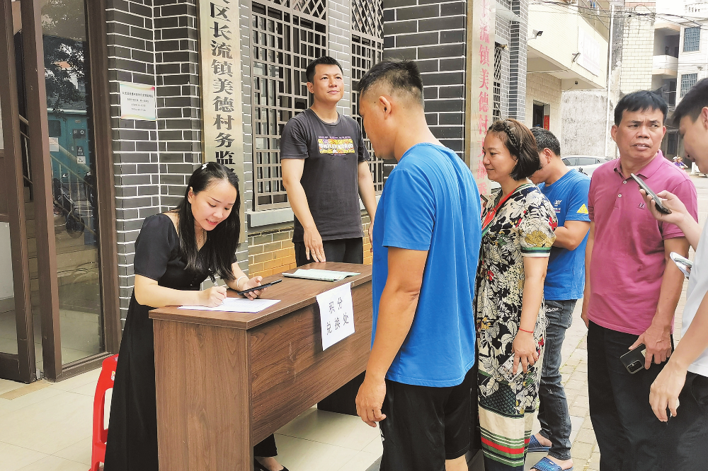 秀英区长流镇美德村村民在积分兑换处登记,准备领取礼品。记者 石中华 通讯员 柴文娅 摄