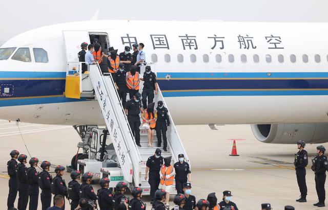 电信诈骗嫌犯被押解下飞机。新京报记者 李英强 摄