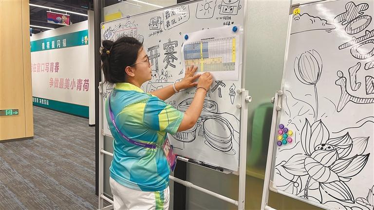 配图:“小青荷”索朗德吉在张贴赛区赛程表。本报记者 万靖 摄