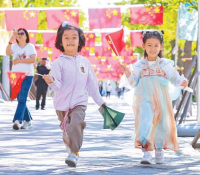 中秋国庆假期,在北京园博园银杏大道,数百面国旗飘扬。图为9月30日,小朋友在园博园游玩。潘俊强 李小彬摄影报道