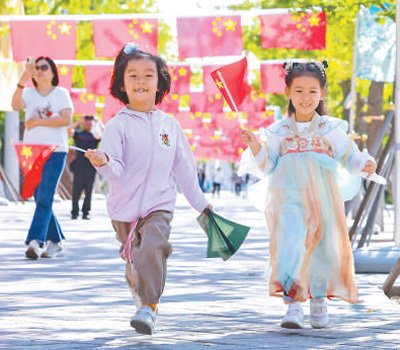 中秋国庆假期,在北京园博园银杏大道,数百面国旗飘扬。图为9月30日,小朋友在园博园游玩。
