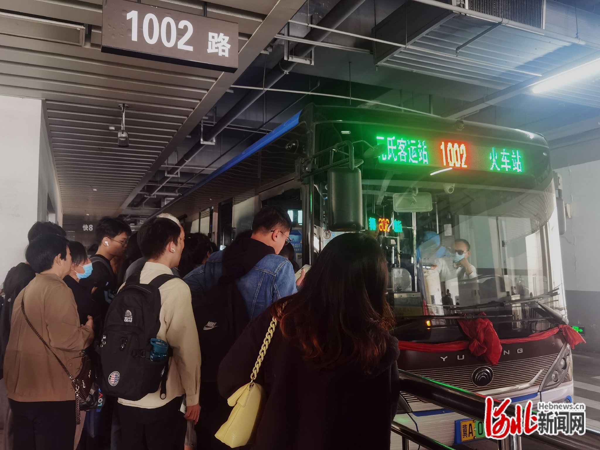 乘客在石家庄火车站西广场乘坐1002路公交车。(王怡文/摄)