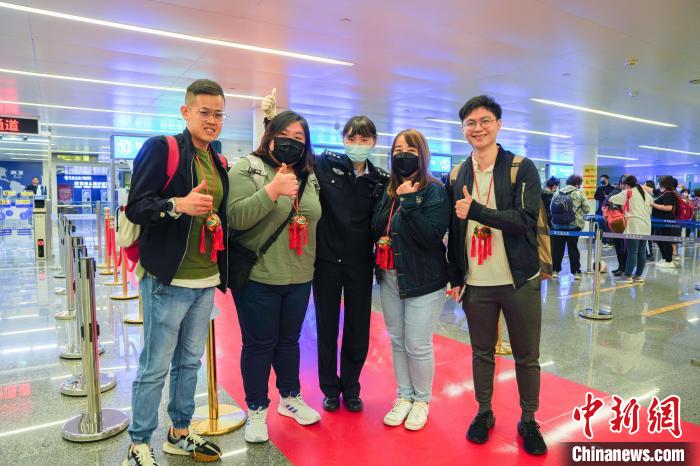 12月2日，馬來西亞旅客手持寓意平安和祝福的壯族繡球在南寧機場合照。梁簫 攝