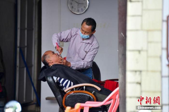   圖為在文昌鋪前騎樓老街，一家理髮店的老闆正在為顧客刮臉。 中新網記者 駱雲飛 攝