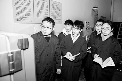 于华南(左一)与学生在实验室研究沥青路面绿色耐久新材料。资料图片