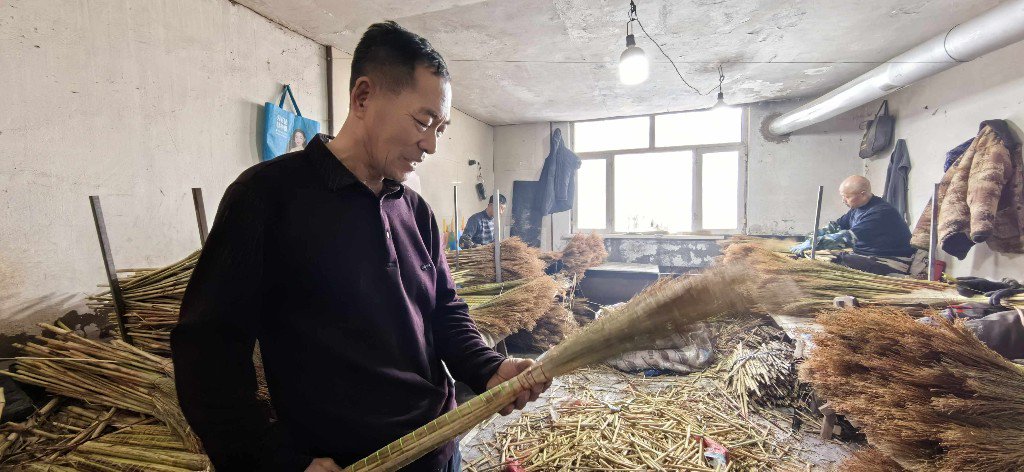 张志明在检查笤帚质量