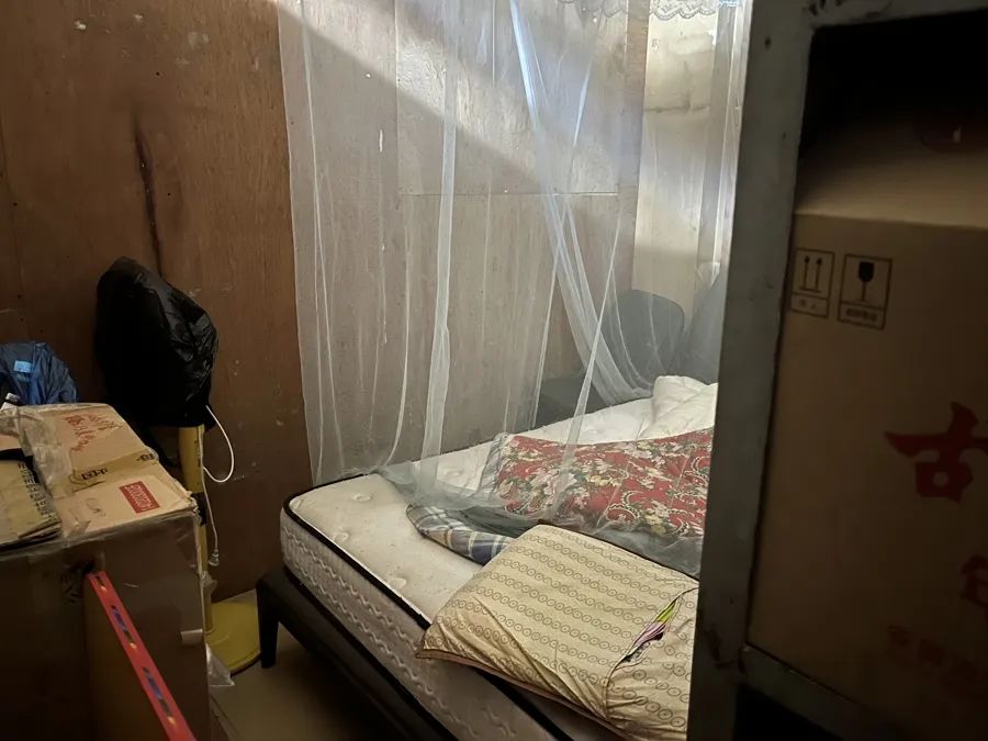 超市堆满货架的仓库里,竟然藏着一张床(吕佳 摄)
