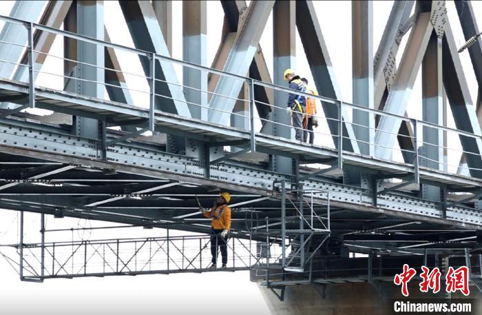 1月25日，衡陽工務段橋隧工在「移動吊籃」上檢查洣河鐵橋底部鋼樑。劉歡攝