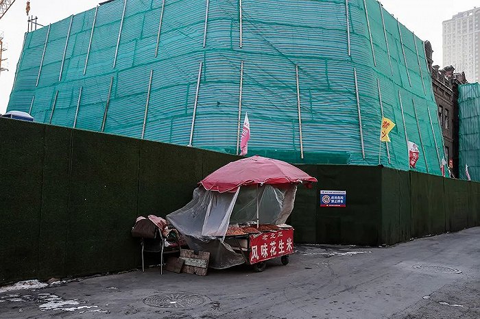 一个花生米摊摆在被绿布包裹的老欧式建筑前。