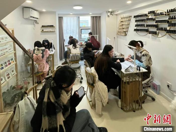 图为美甲师正在忙碌,一旁的沙发上正有几名顾客在排队等候。刘洋摄