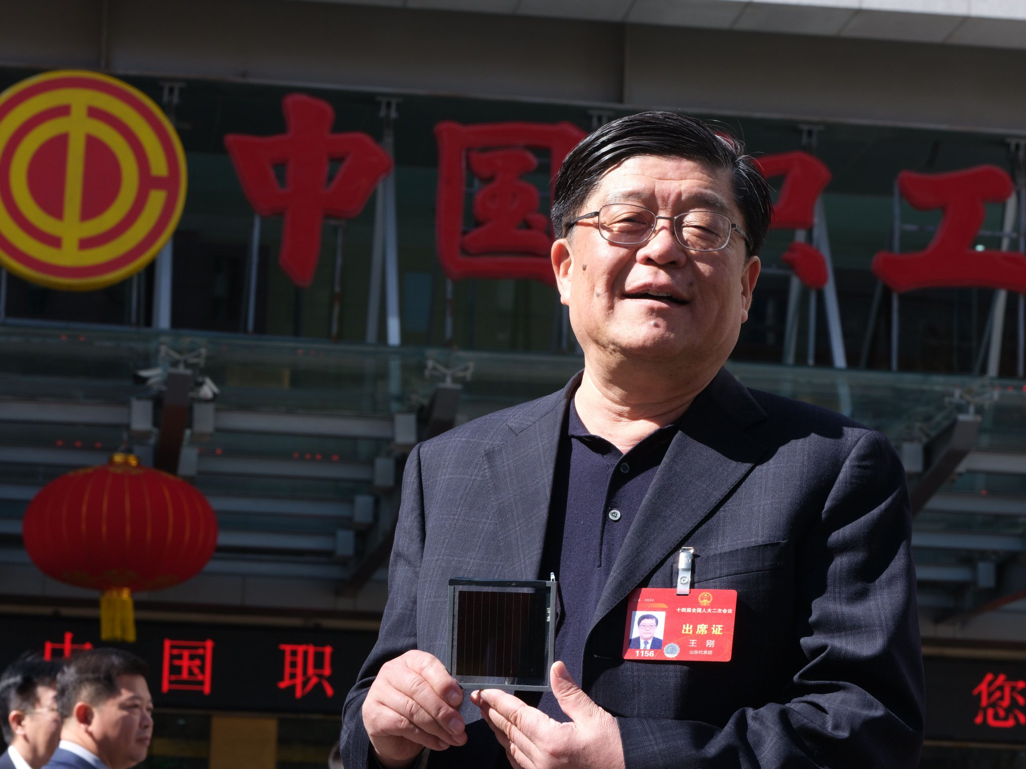 全国人大代表、金晶科技董事长王刚手持金晶超白TCO导电膜玻璃新成果参加今年两会 公司供图