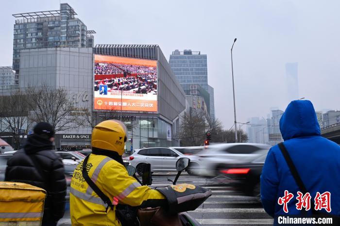 3月5日，十四屆全國人大二次會議在北京人民大會堂開幕。圖為北京一戶外大屏播放開幕會。中新社記者 趙文宇 攝