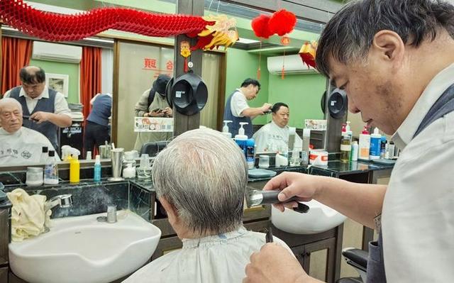 3月11日，四联美发王府井店，理发师为排在第一位的顾客理发，老先生不到6点就在门口排队了。新京报记者 薛珺 摄