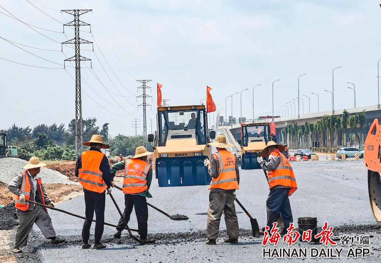3月22日,在G15沈海高速公路海口段地面市政道路项目,工人正在铺设路面沥青。