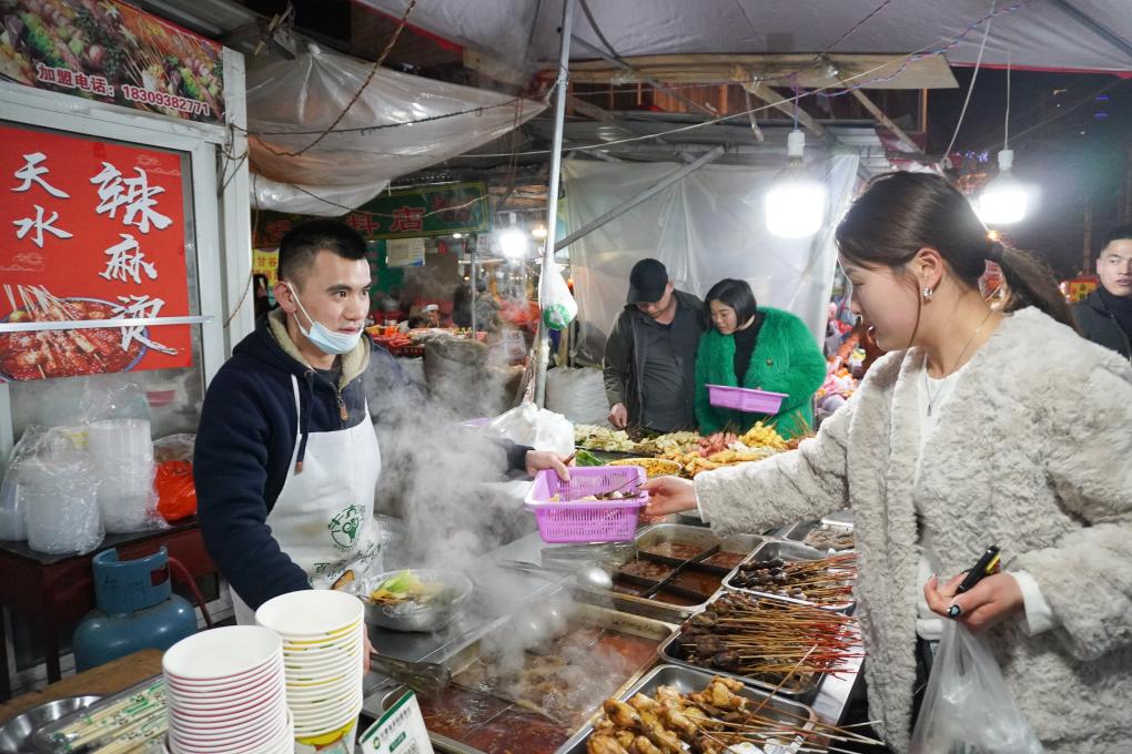 3月19日，在天水市秦州區的一條小吃街，顧客在一處麻辣燙攤位選購麻辣燙。新華社記者 馬希平 攝
