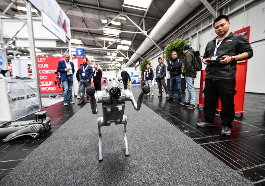 4月22日，在德國漢諾威工博會上，杭州宇樹科技有限公司參展商（右一）在展示一款機器狗。新華社記者任鵬飛攝