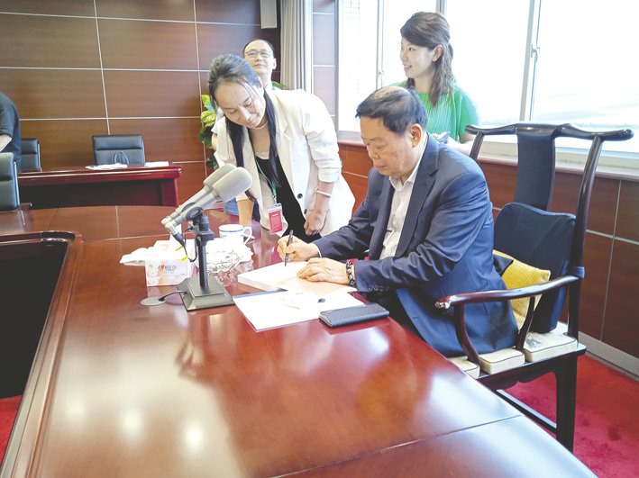 股东大会期间,参会股东请曹德旺在《心若菩提》上签名。每经记者 赵李南 摄