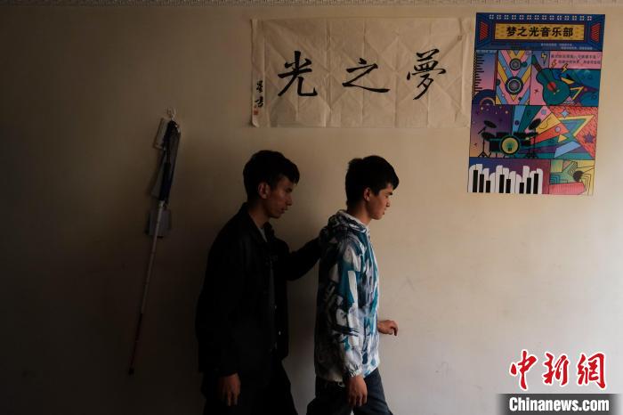 4月28日，西藏首位盲人程序員尼瑪平措(右)與賓捷安紮西走在一幅寫有「夢之光」的書法下。中新社記者 江飛波 攝